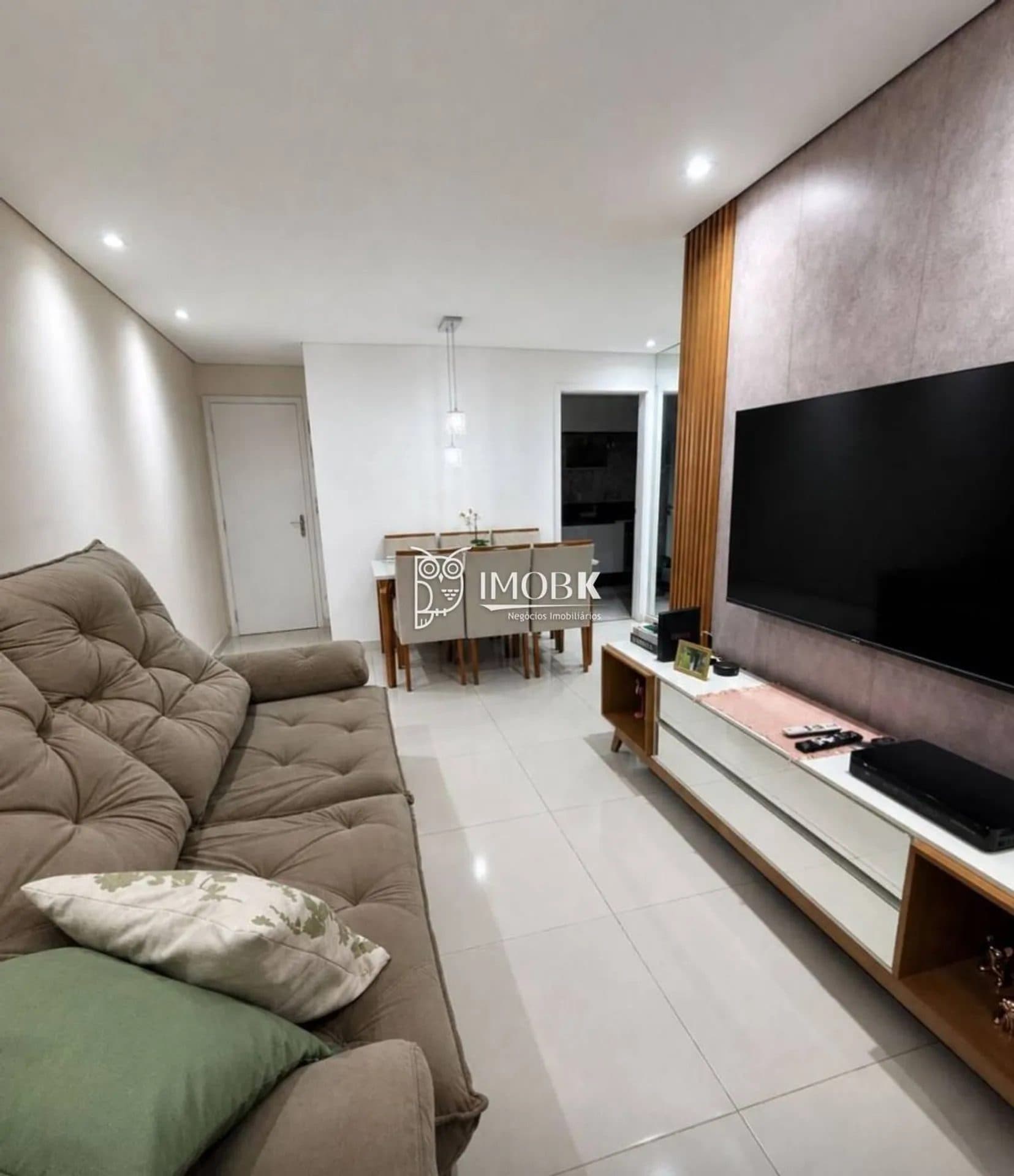 Sala de estar com sofá marrom, painel de TV e iluminação embutida no teto.
