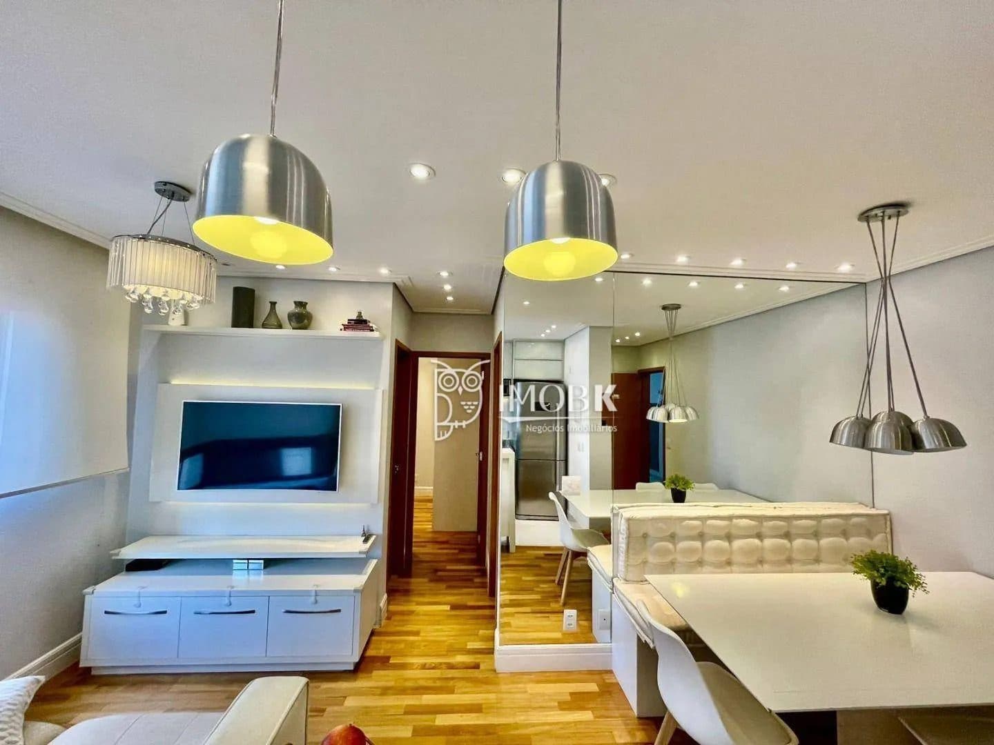 Sala de estar e jantar integrada com piso de madeira, rack para TV e mesa de jantar.