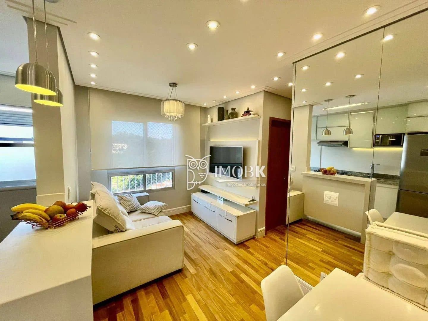 Sala de estar com sofá cinza, rack branco, TV e janela com persiana rolo.