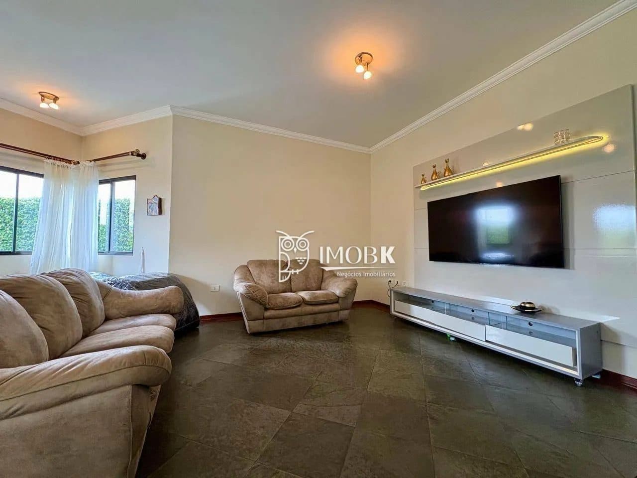 Sala de estar com sofás e painel para TV.