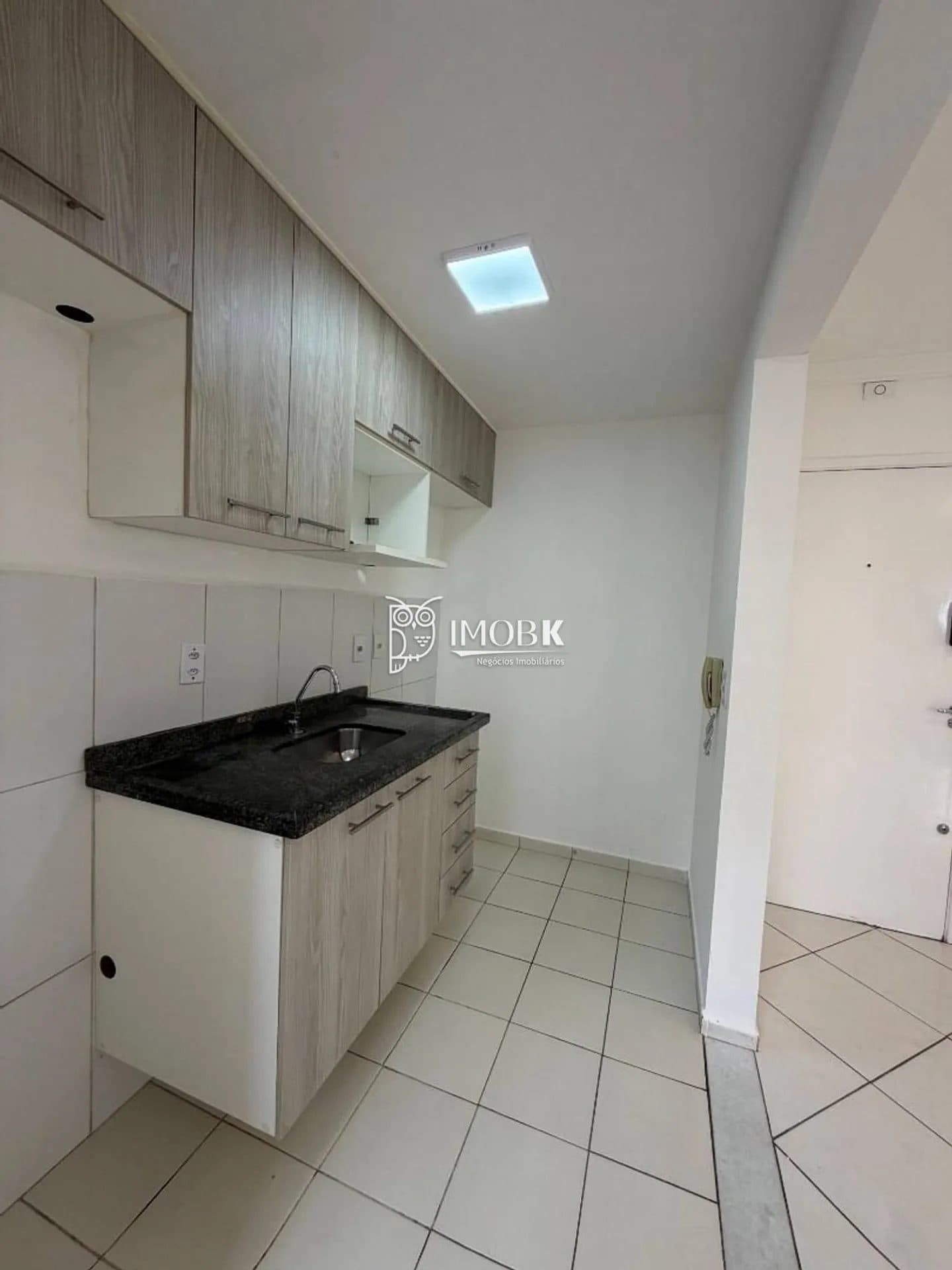 Cozinha compacta com pia em granito preto, armários planejados e piso cerâmico claro