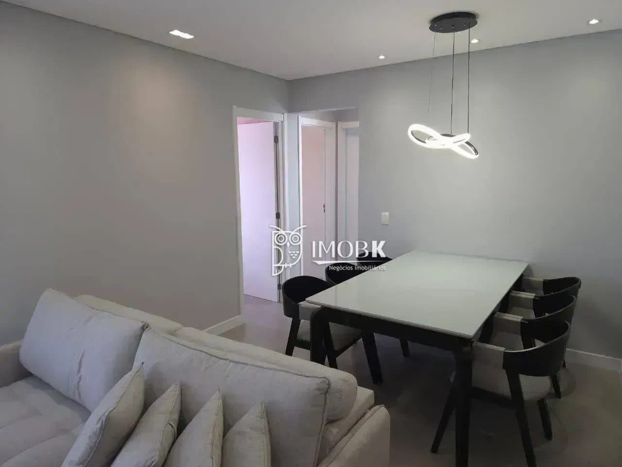 Área de jantar integrada com mesa com tampo de vidro e cadeiras pretas.