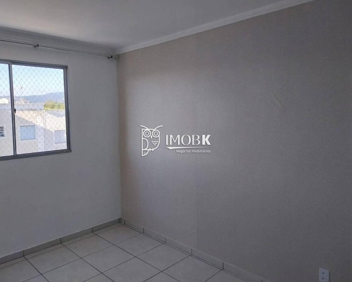 Sala de estar com piso claro em cerâmica, parede com revestimento texturizado e janela com vista externa.
