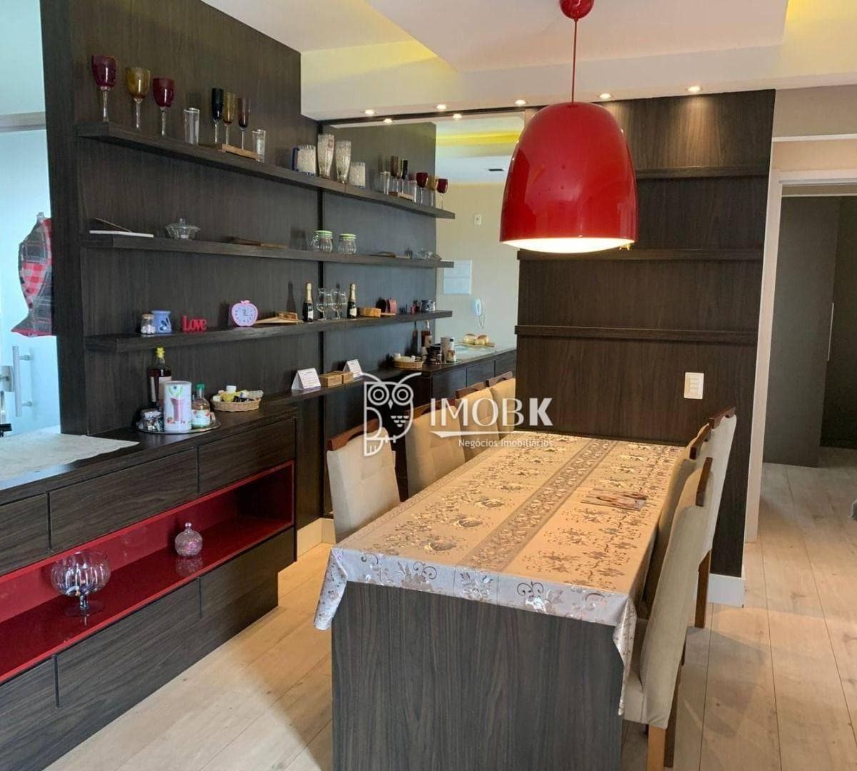 Sala de jantar integrada com mesa com cadeiras e estante planejada em tom escuro.