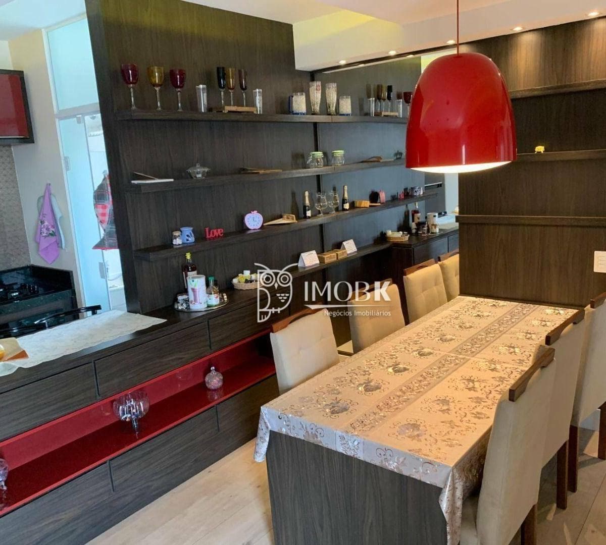Sala de jantar com mesa posta, estante com prateleiras e pendente vermelho.