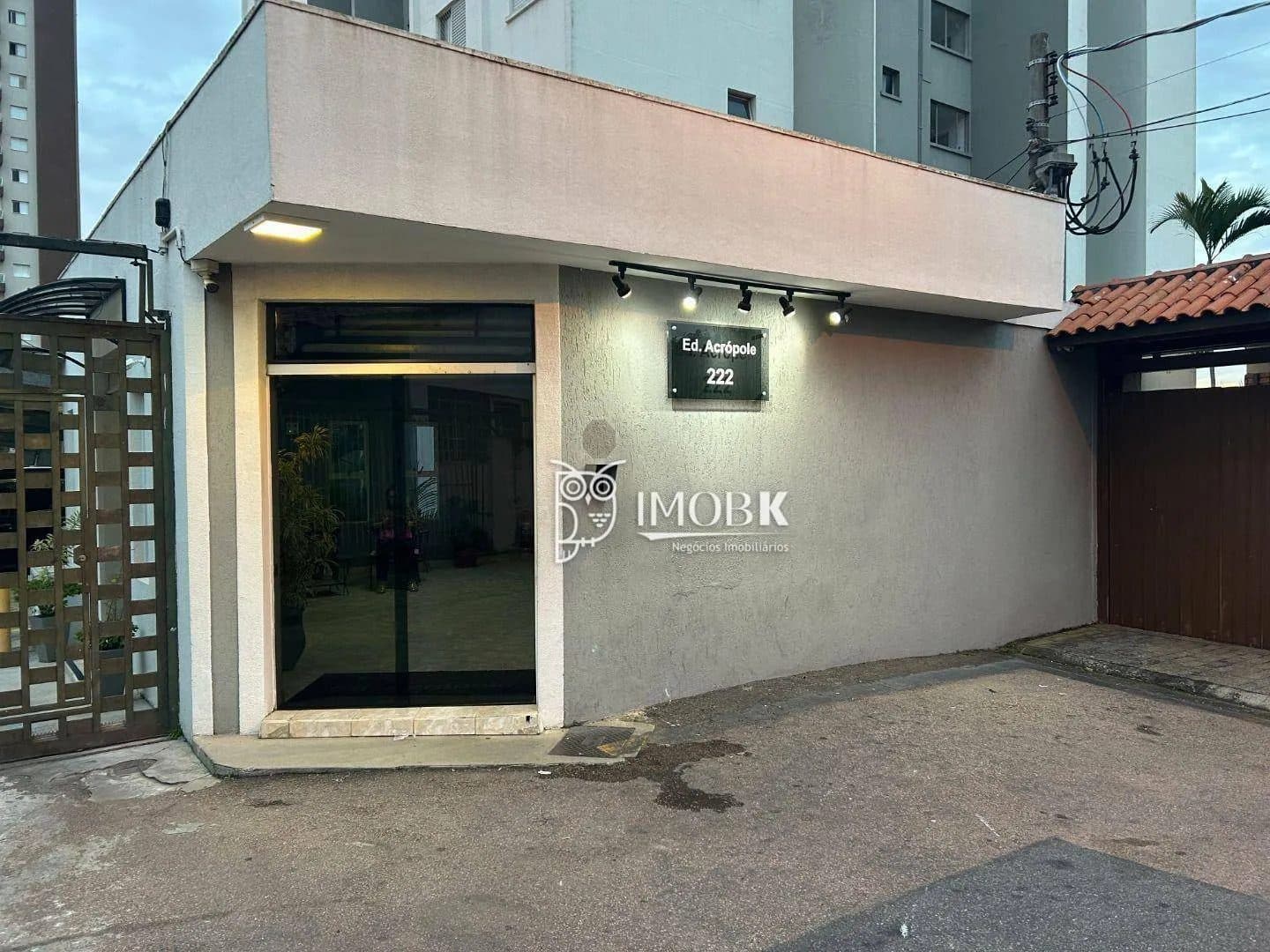 Fachada externa do edifício com portão de entrada e placa de identificação.