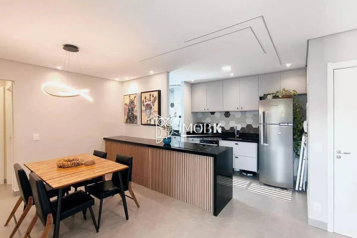 Sala de jantar integrada com cozinha americana e balcão em tom amadeirado com bancada preta.