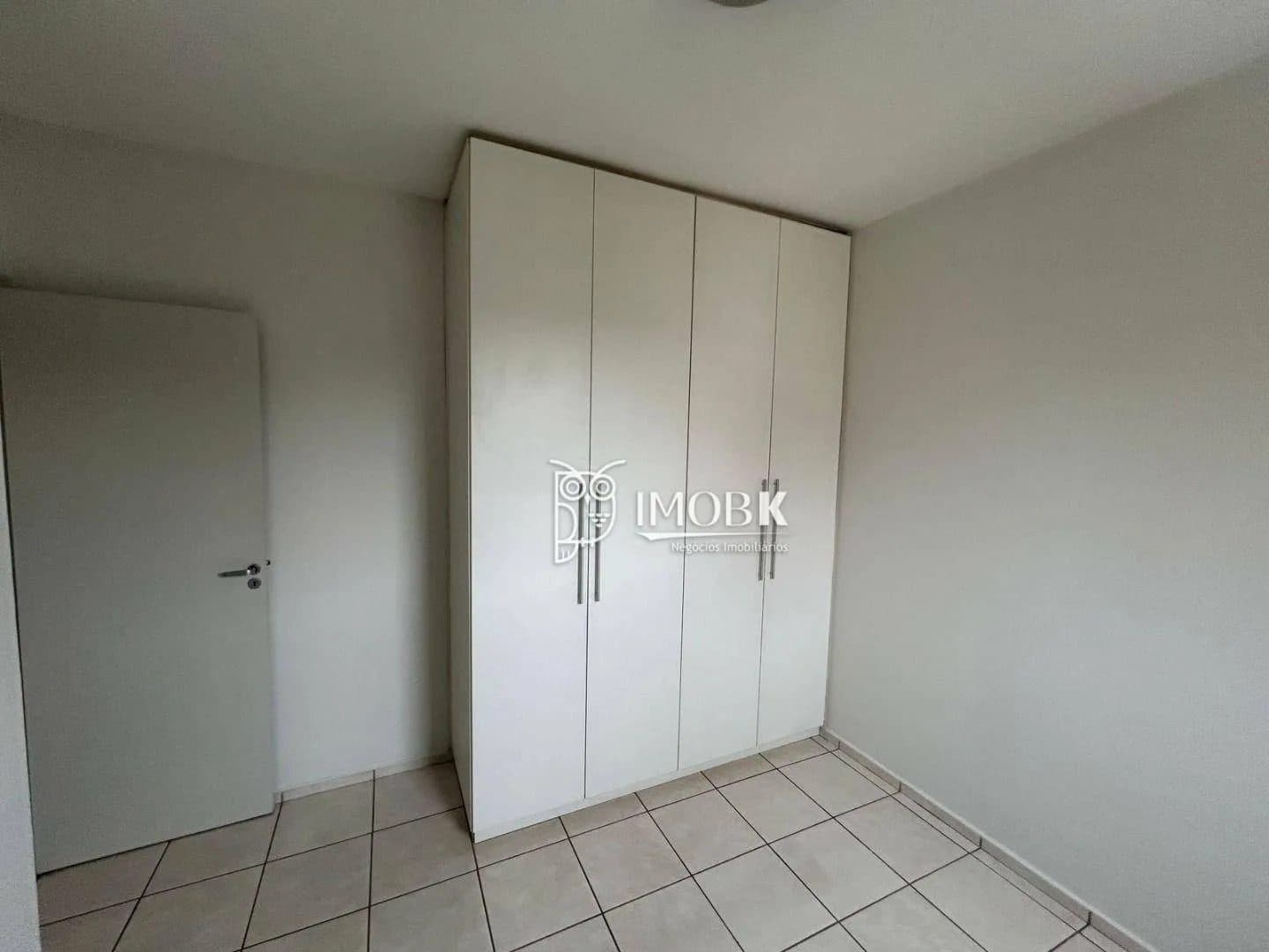 Quarto com piso em cerâmica, paredes claras e armário embutido branco.