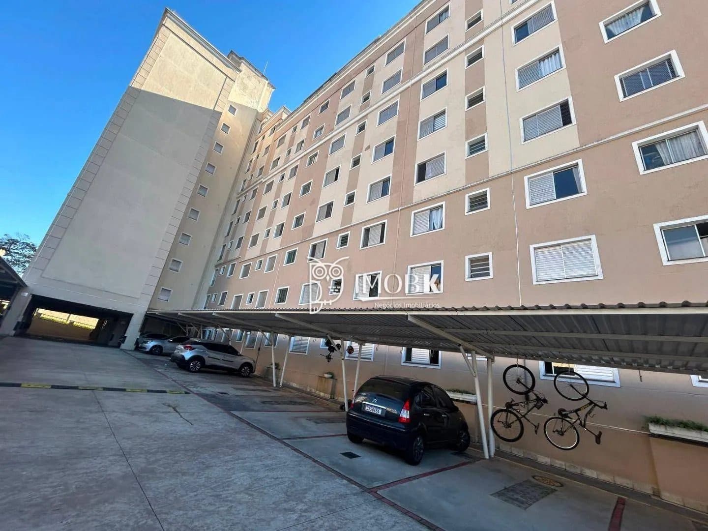 Fachada do edifício residencial com pintura em tons de bege e estacionamento coberto.