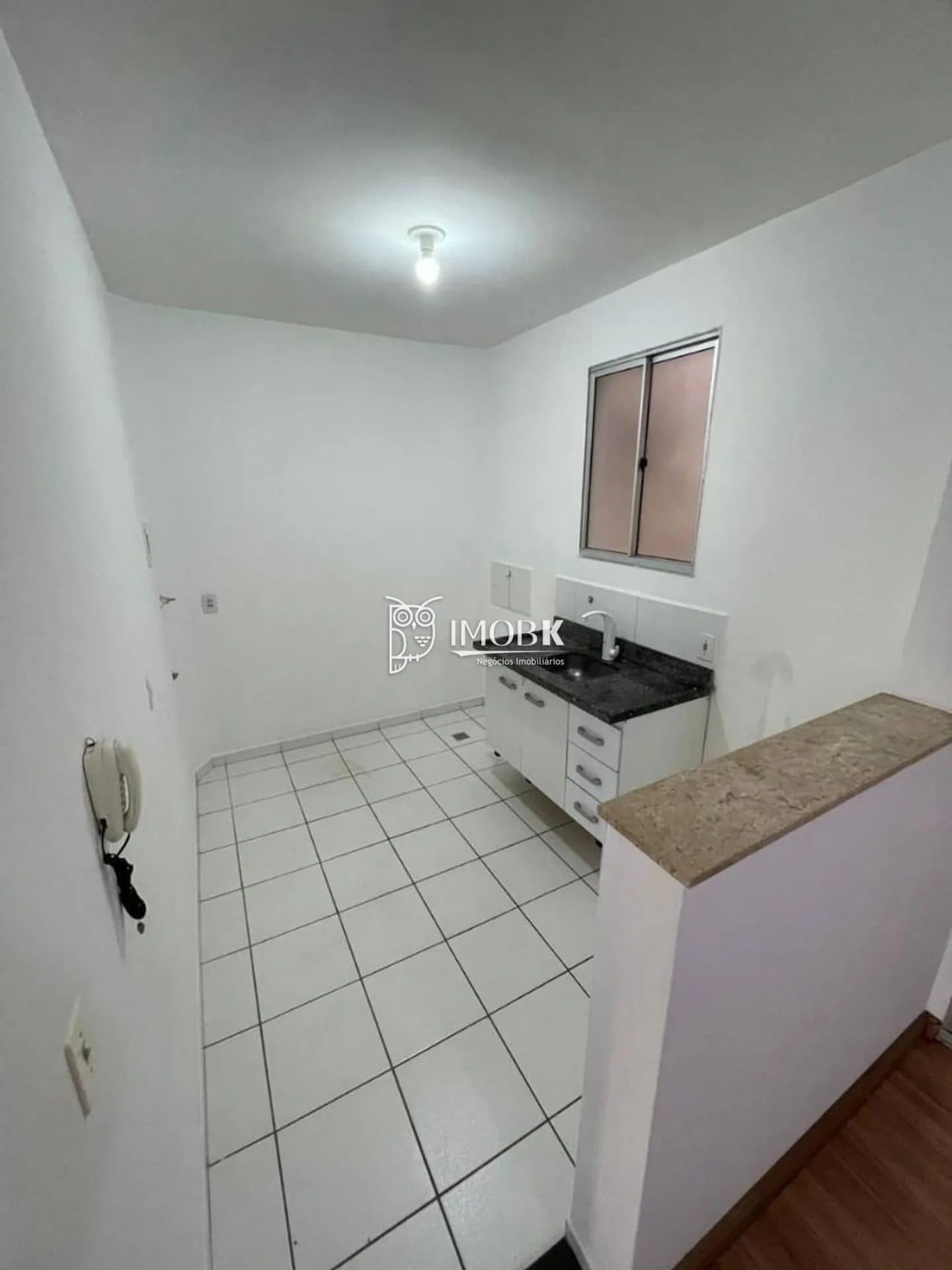 Cozinha compacta com piso de cerâmica branca, bancada em granito escuro e gabinete.