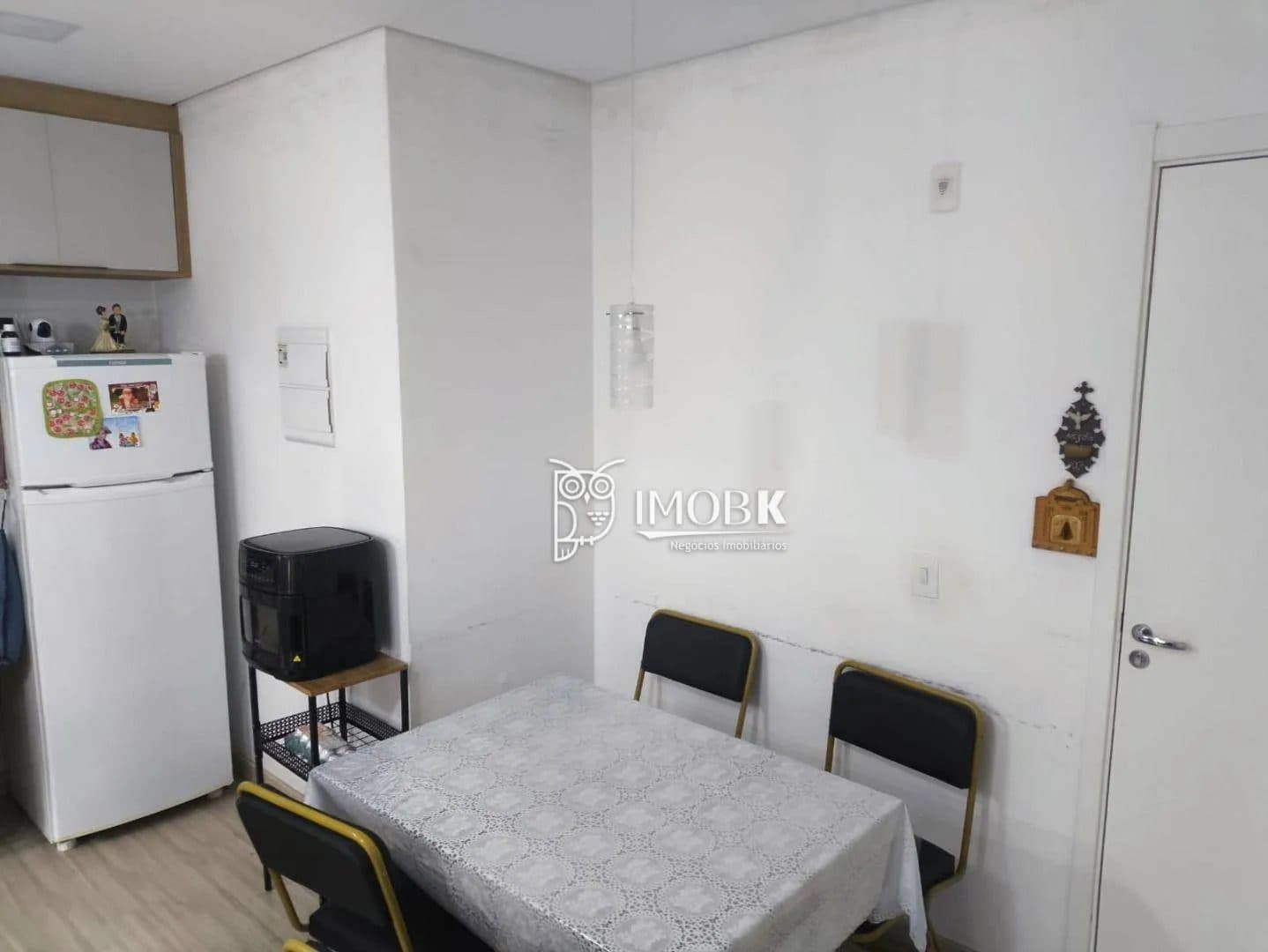 Sala de jantar integrada com mesa coberta por toalha e quatro cadeiras.