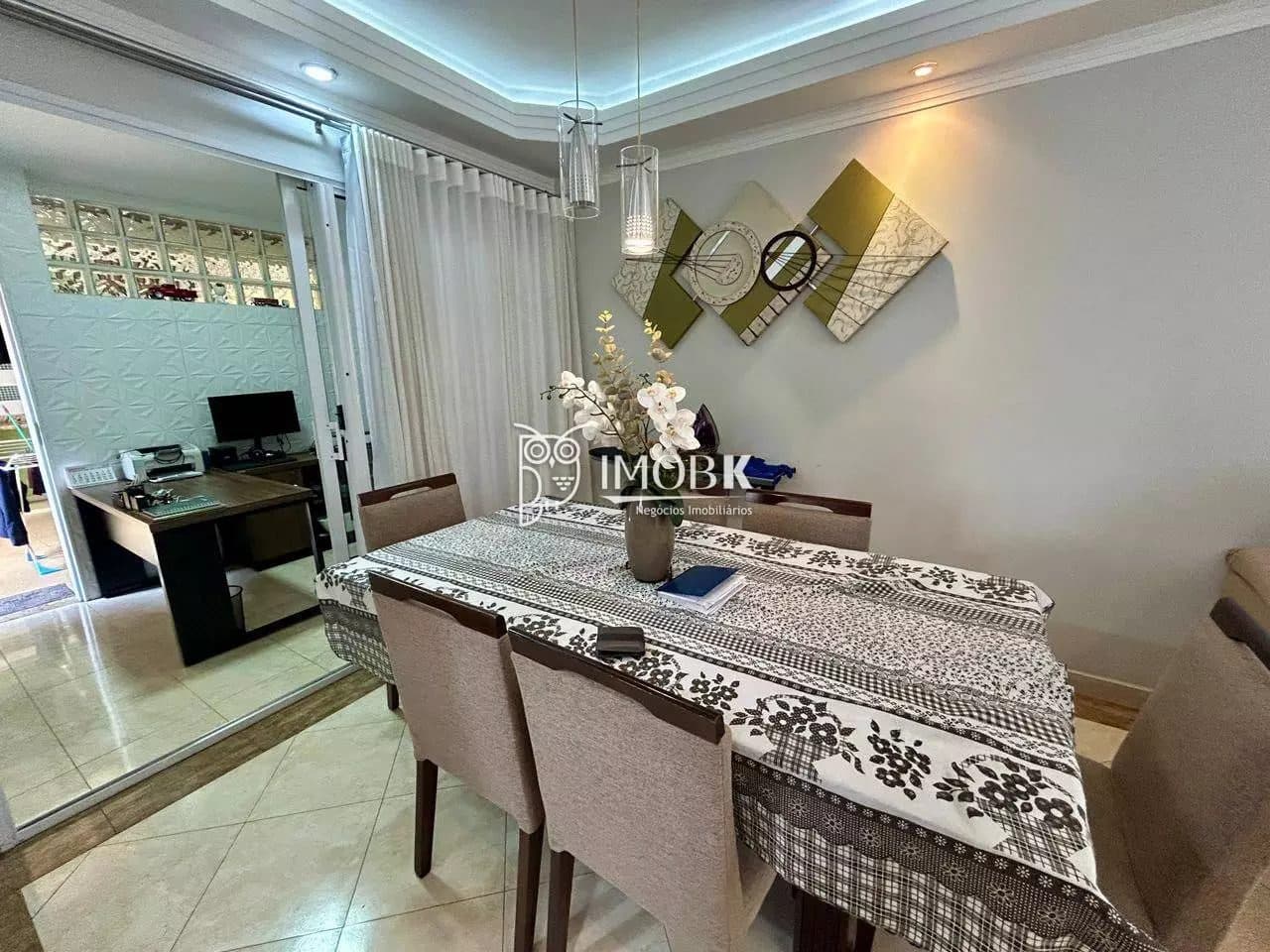 Detalhe da mesa de jantar com toalha estampada, arranjo floral e decoração na parede.
