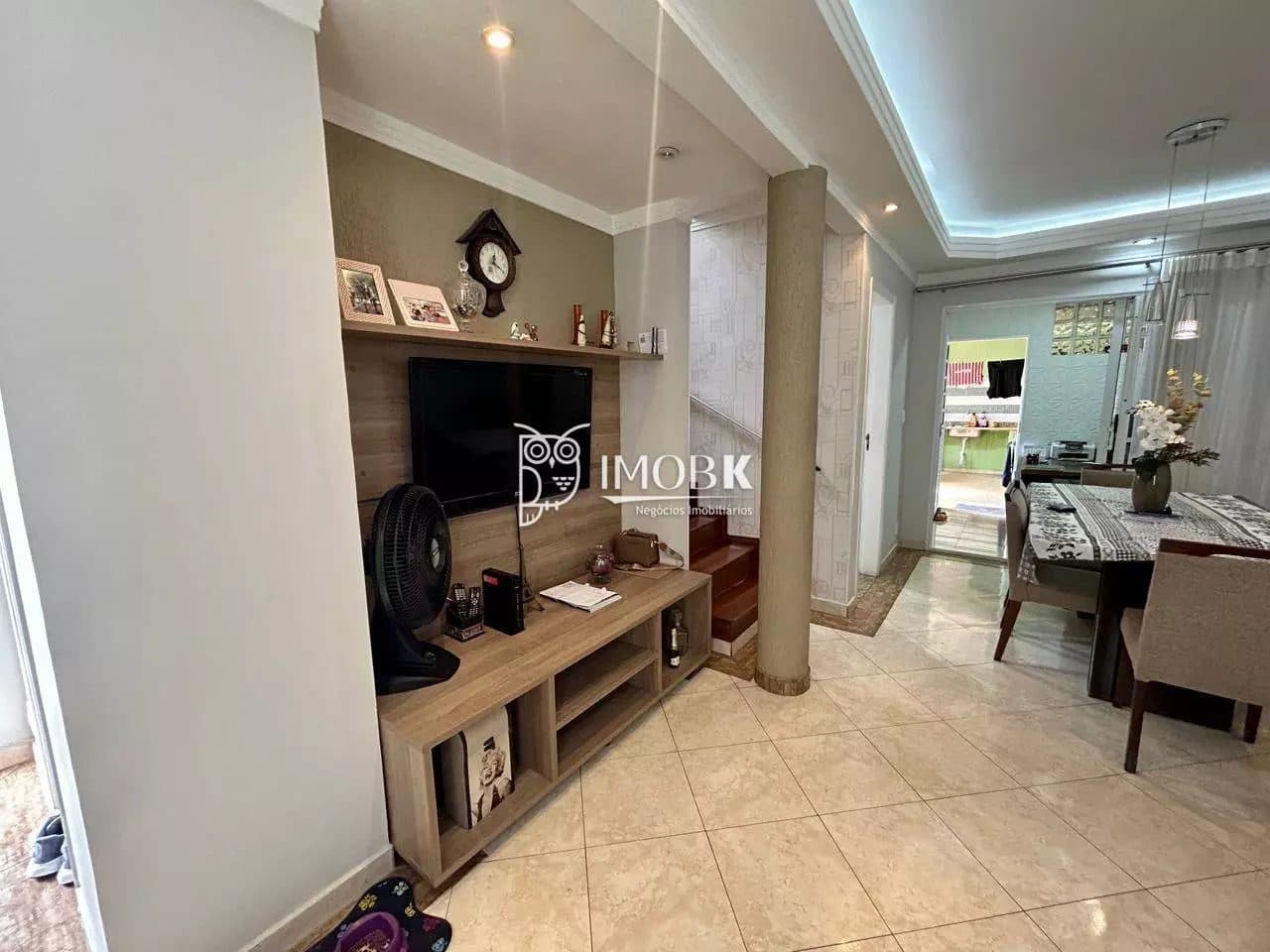 Sala de estar com painel para TV em madeira, rack e itens decorativos.