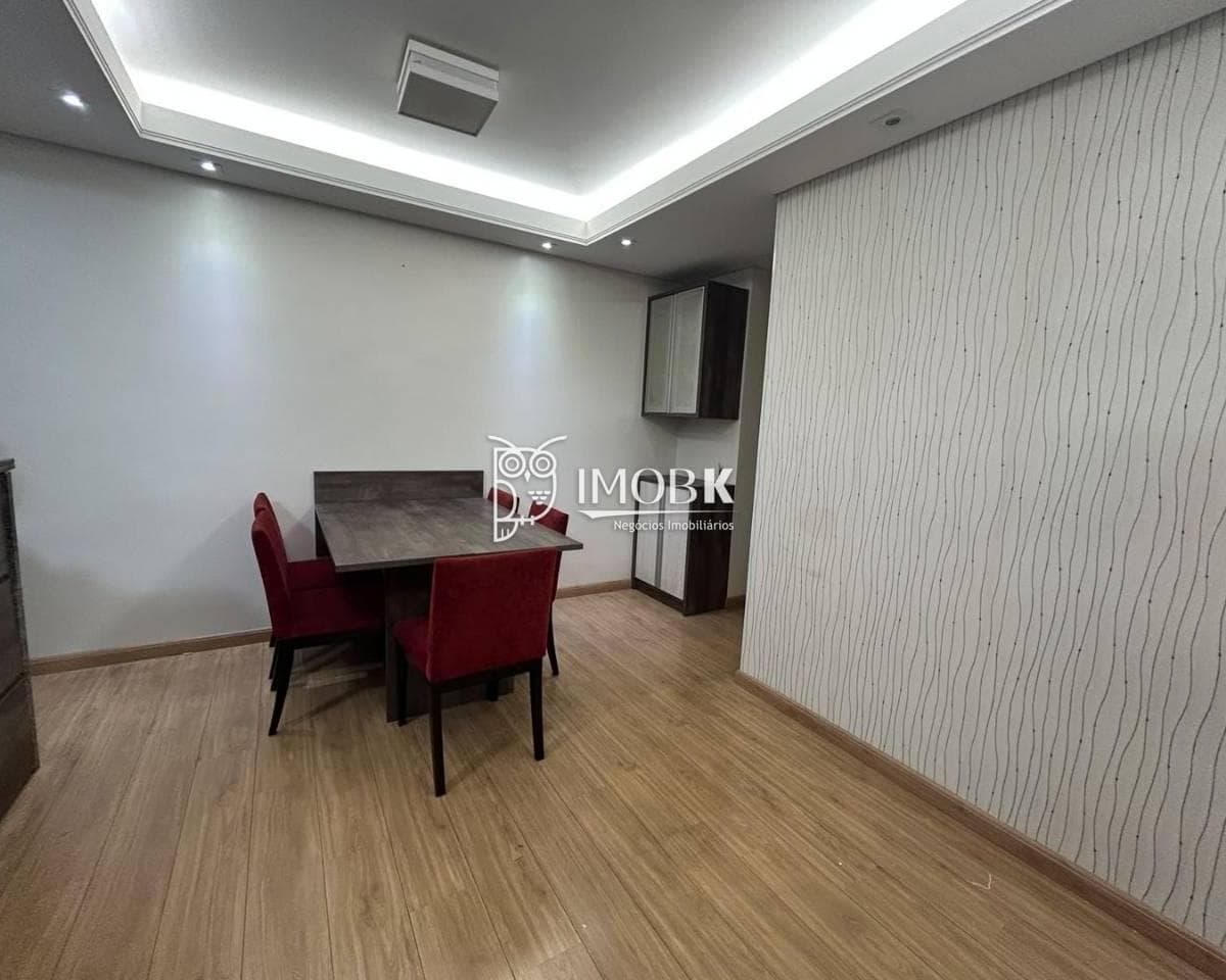Sala de jantar integrada com piso amadeirado, mesa com cadeiras vermelhas e rebaixo de gesso no teto.