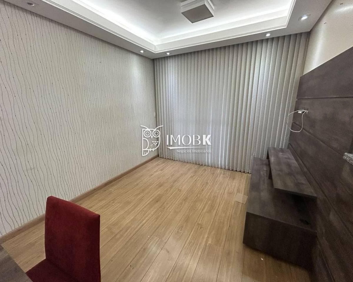 Sala de estar e jantar com piso amadeirado, parede decorada e cortina clara.