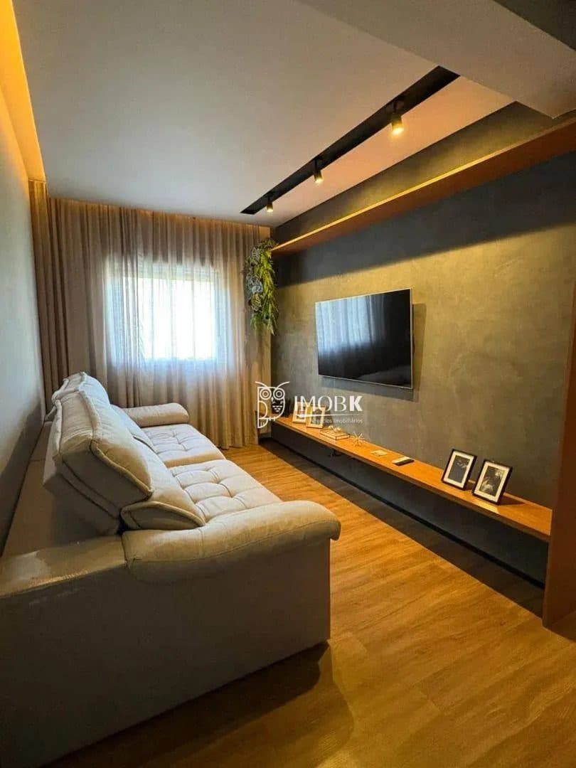 Sala de estar com sofá, parede cinza e painel de TV com prateleira de madeira.