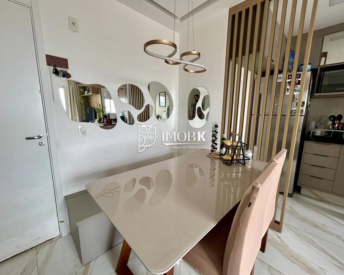 Sala de jantar integrada com mesa com tampo em vidro, cadeiras estofadas e espelhos decorativos na parede.