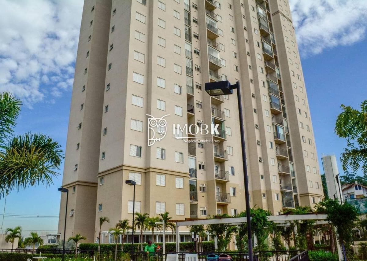 Fachada do edifício residencial de vários andares com pintura em tons claros e varandas.
