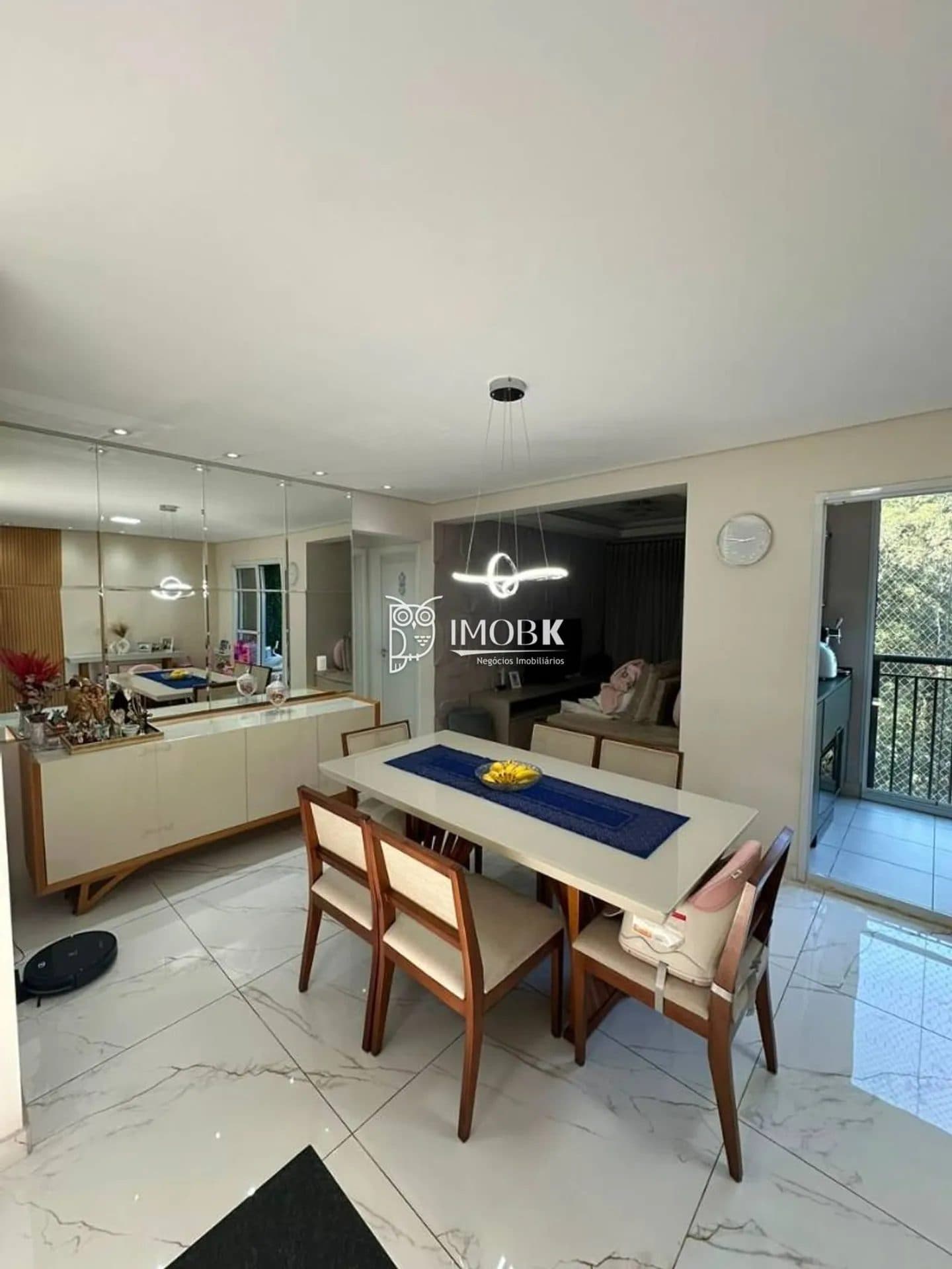 Sala de jantar integrada com mesa para seis lugares, aparador e parede espelhada