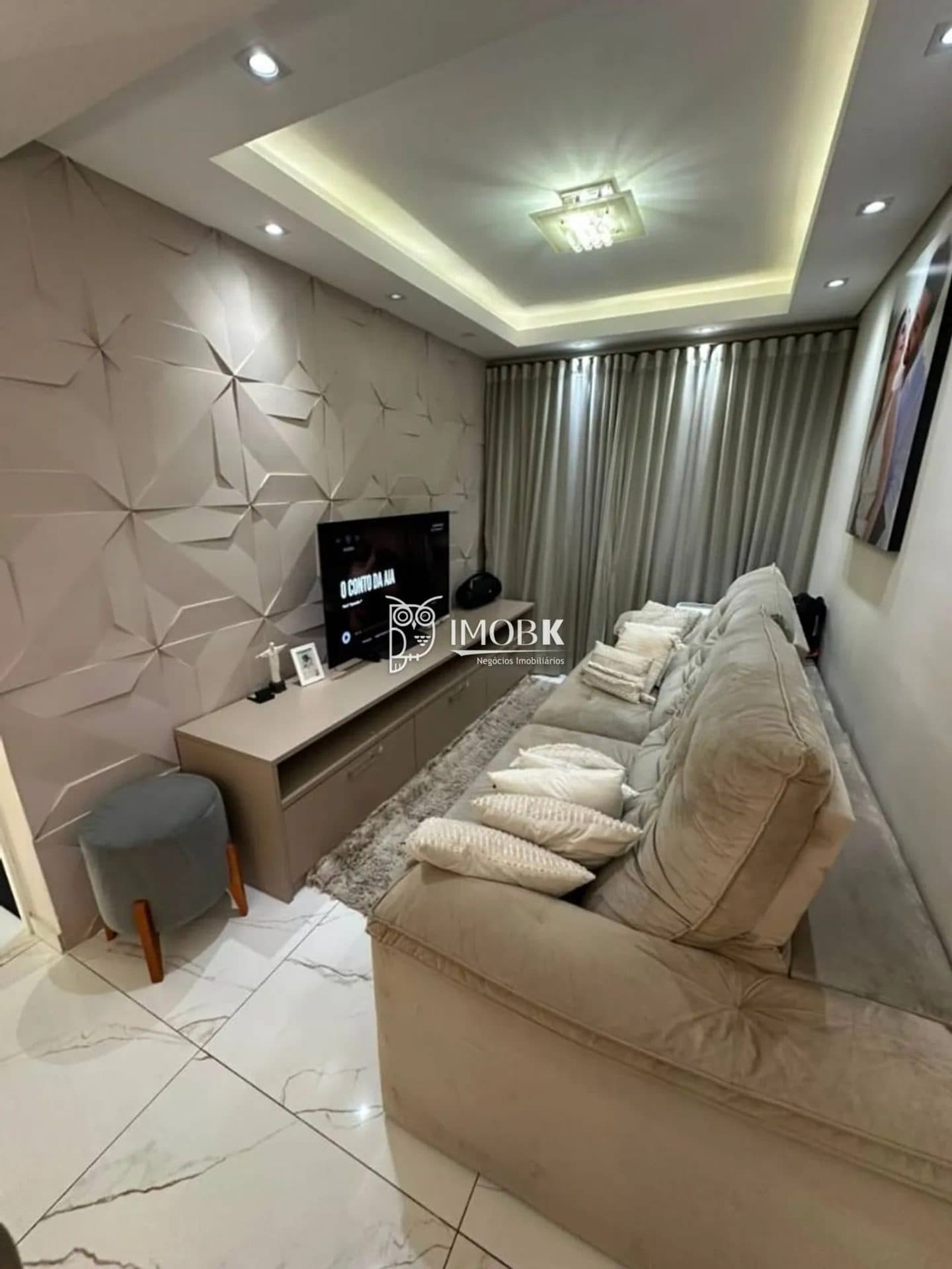 Sala de estar com sofá grande, painel para TV e parede revestida em 3D